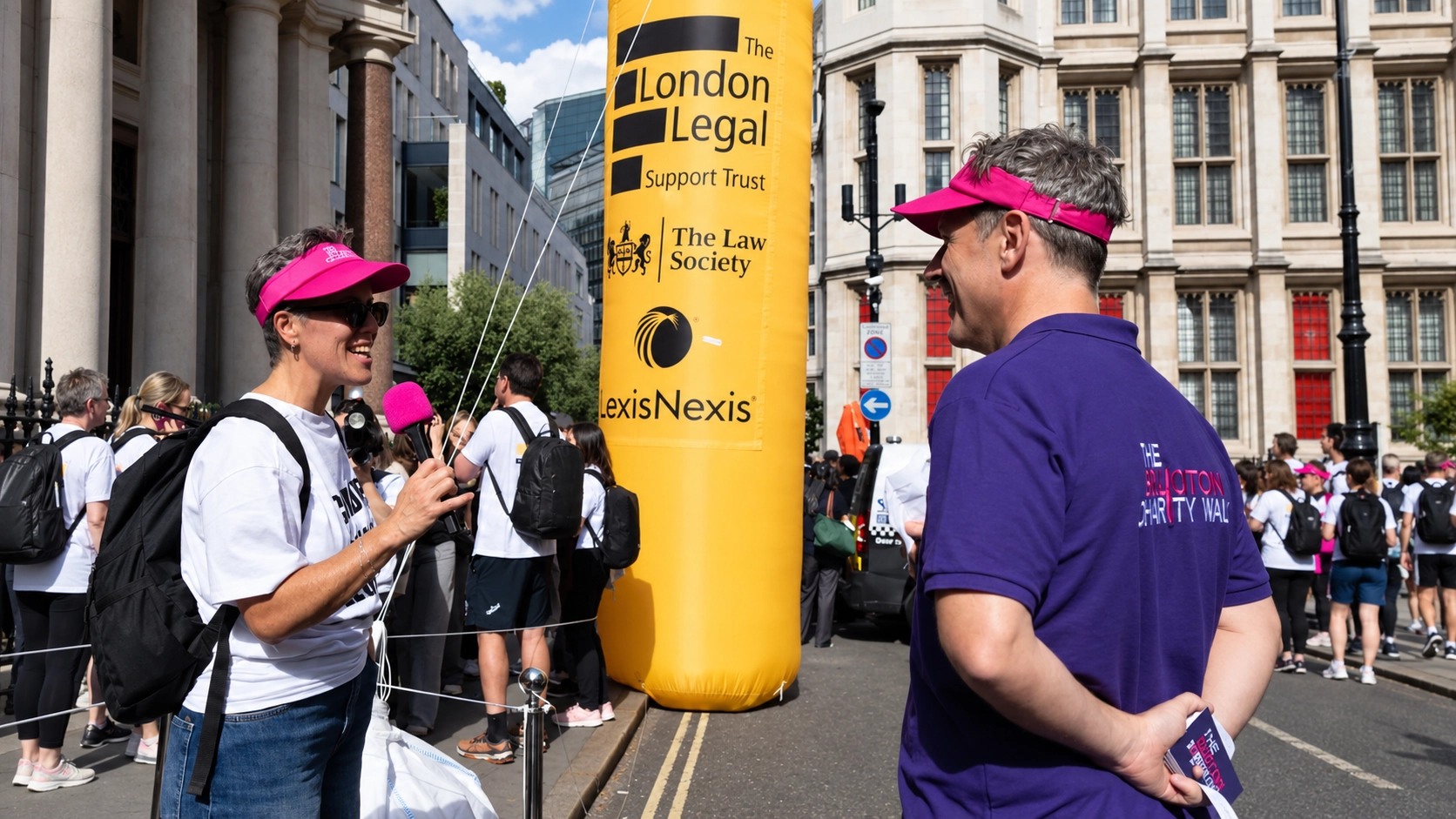woman in pink hat interviewing man in pink hat at the annual Legal walk event in London.