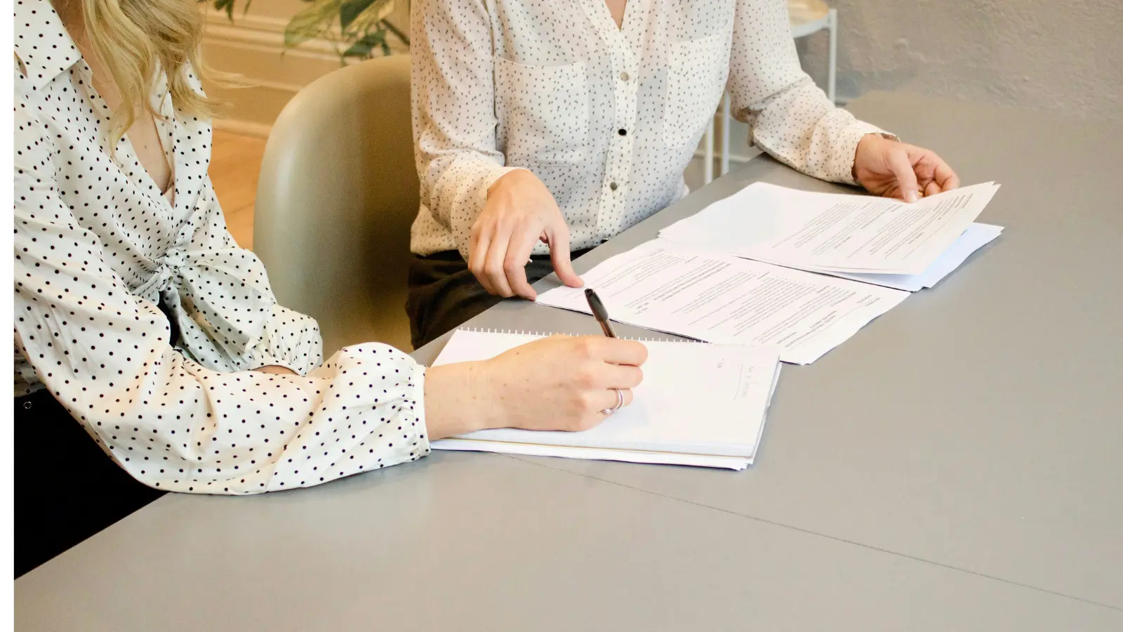 Two women lawyers signing documents only their arms are visible